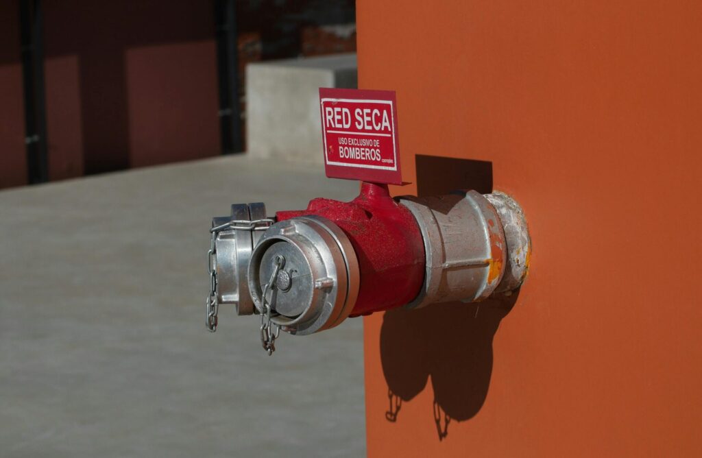 Conexión de fachada para redes de hidrantes y sistema de columna seca instalada por Othrik Fire en Barcelona, con cartela roja de "Uso exclusivo bomberos